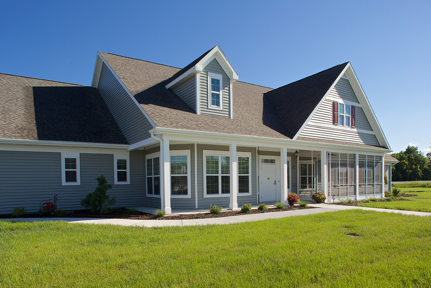 A cottage with a covered porch and green lawn