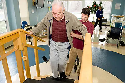 A physical therapist guiding a resident as he walks