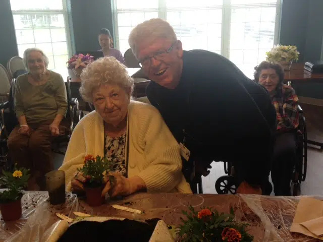 Residents and a staff member potting flowers together at a table