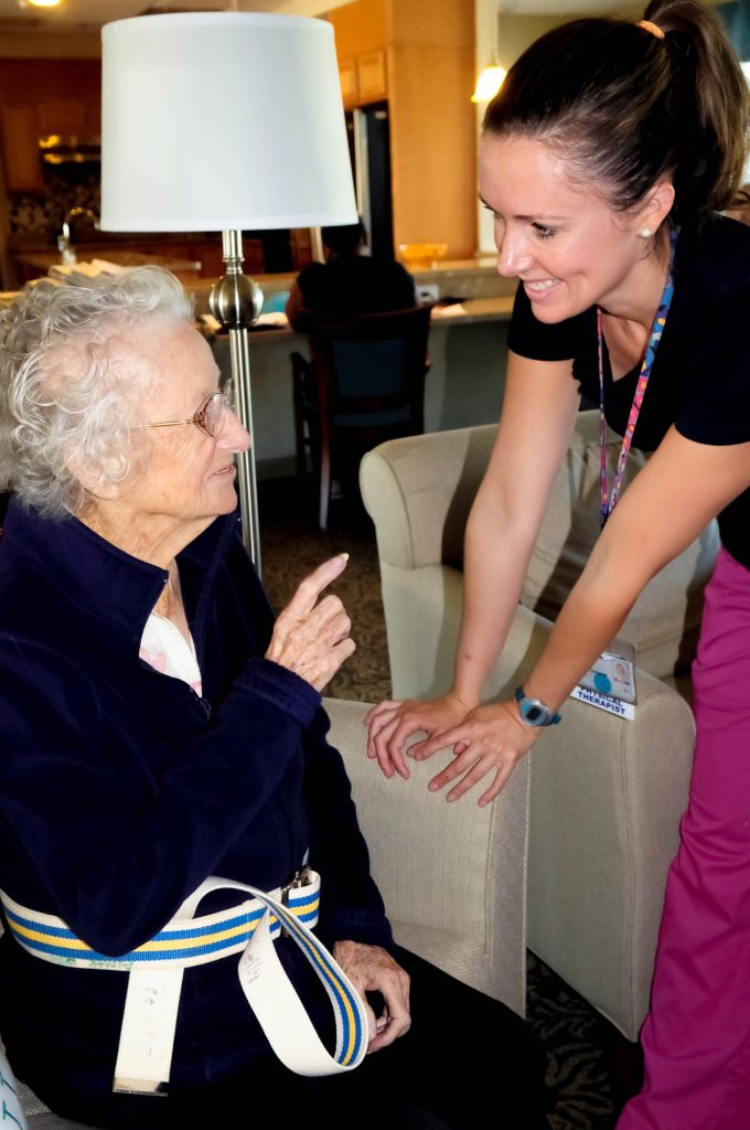 A staff member helping a resident in her room