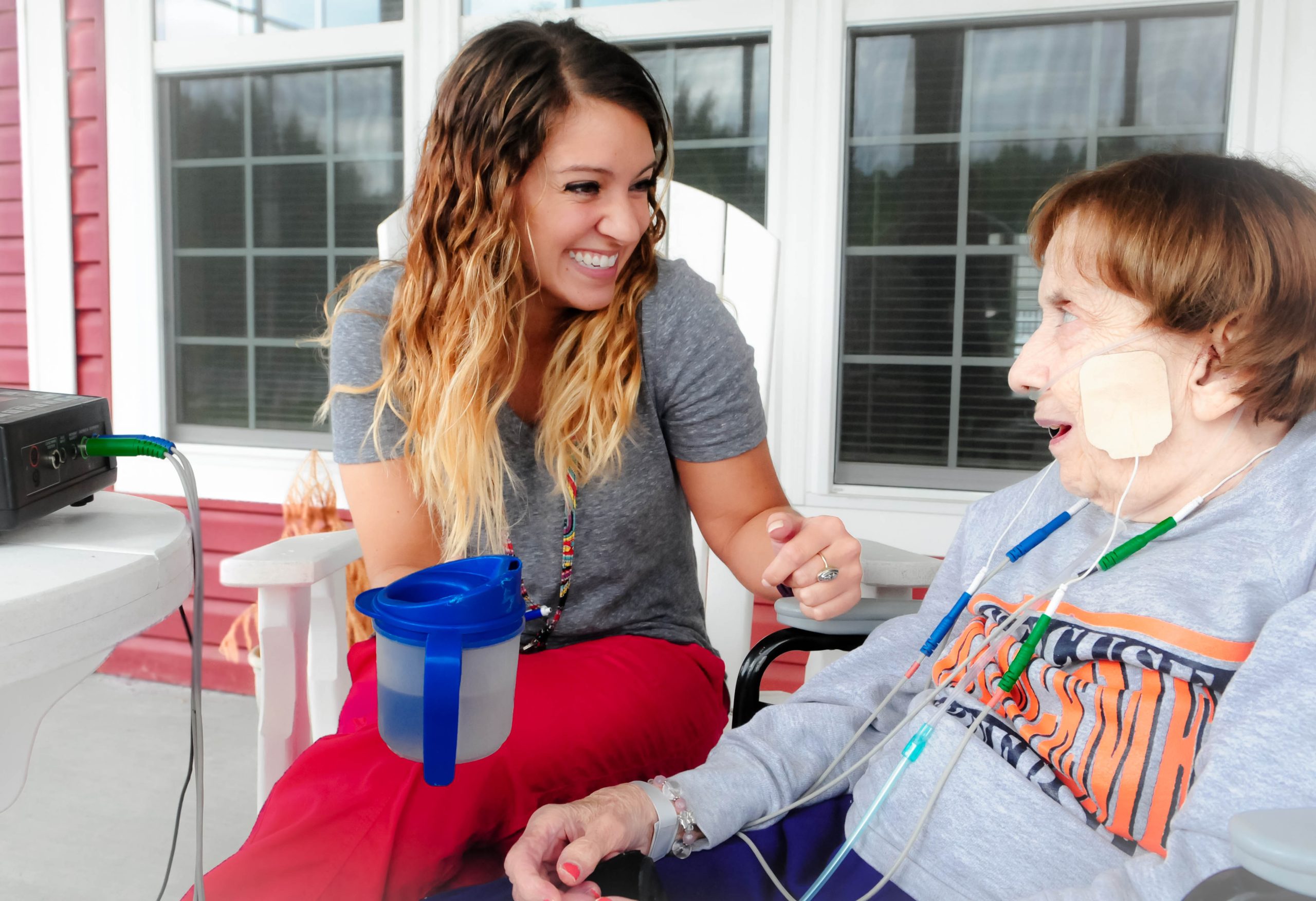 A smiling caregiver talking with a resident on a cottage porch