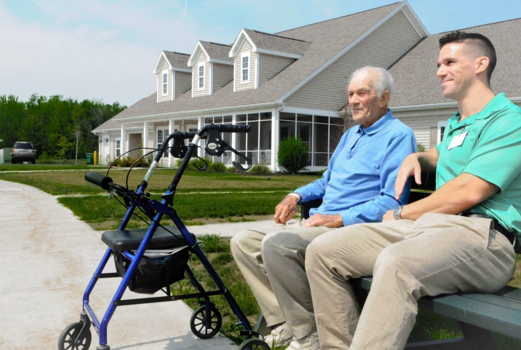 A therapist and a resident sitting on a bench outside