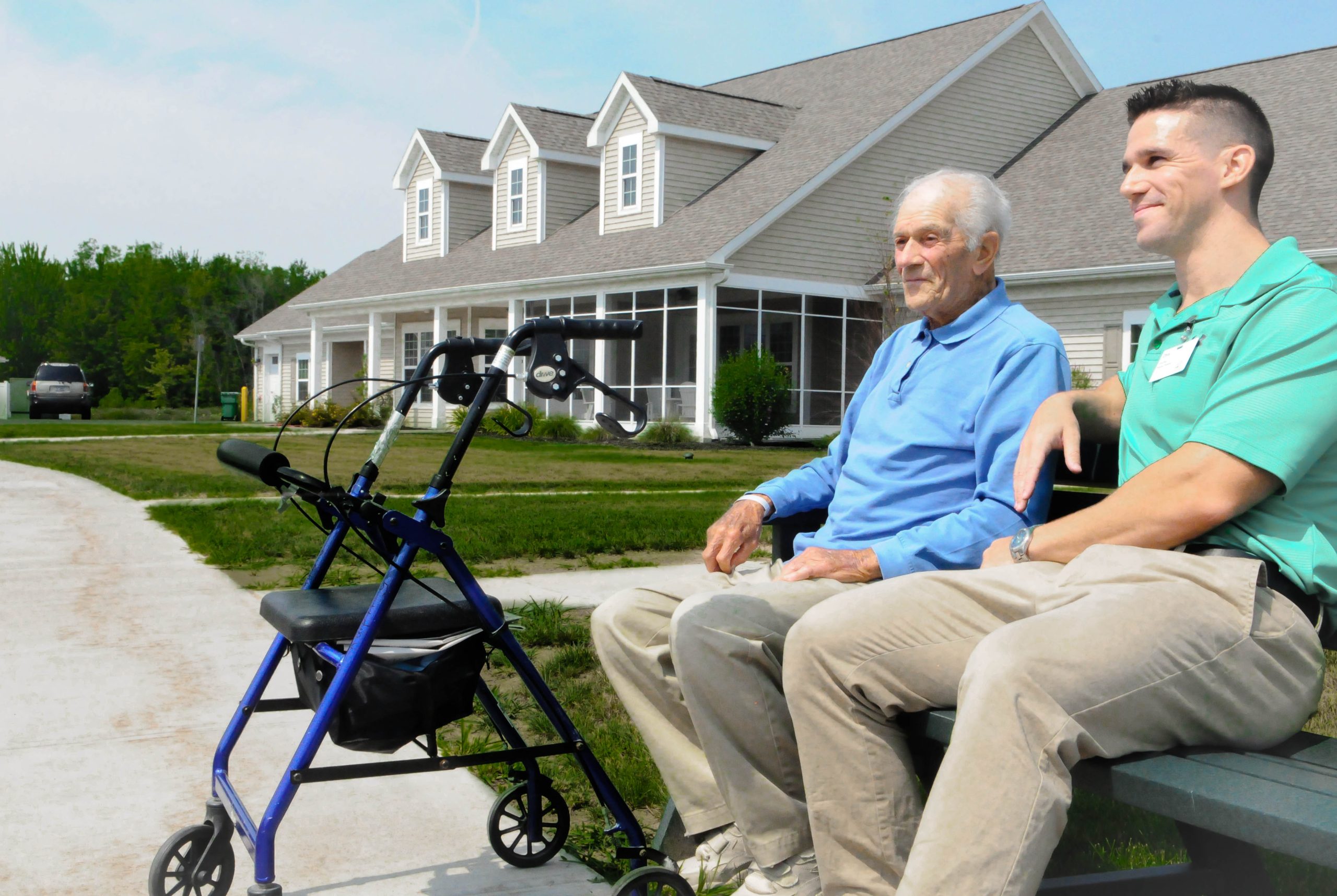 A therapist and a resident talking on a bench outside a cottage