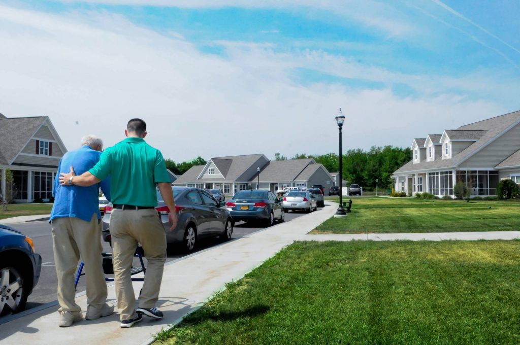 A therapist and a resident walking together outside the cottages